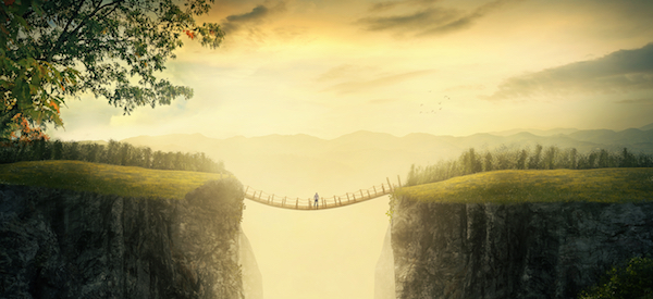 A man stands alone on a bridge between two mountains.