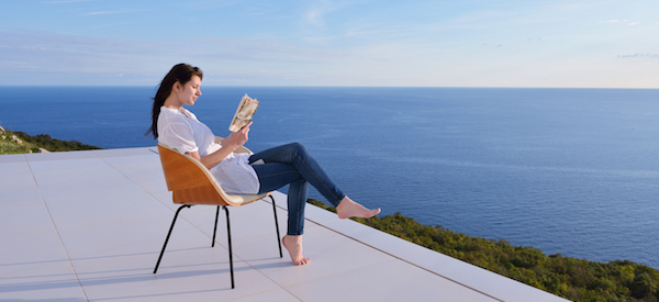 handsome young man relaxing and working on laptop computer at home balcony while looking sunset